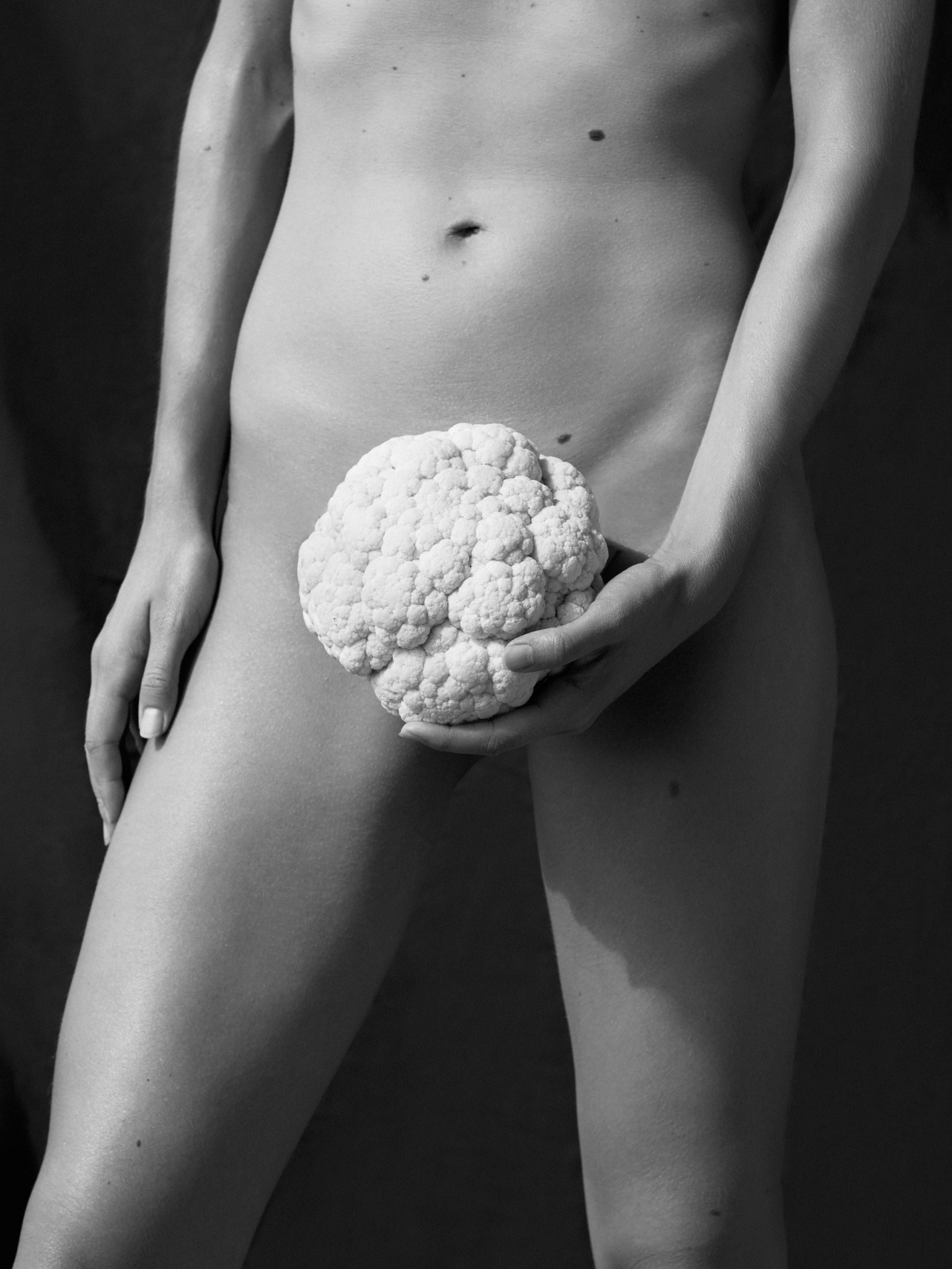 Black and white photo of nude woman with cauliflower